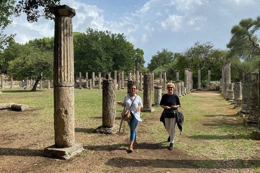 Two people walking among ancient stone columns in a historical site. 1