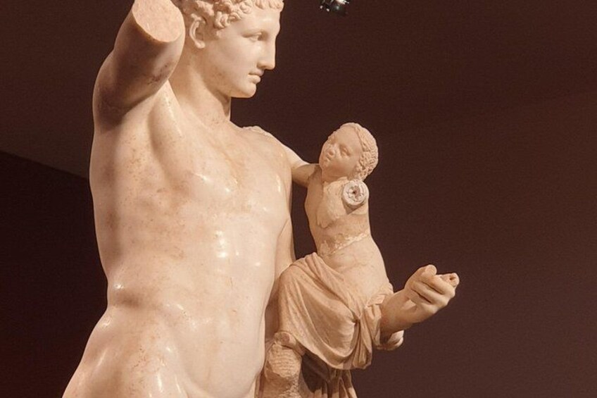 A marble statue of a standing male figure with a child. 3