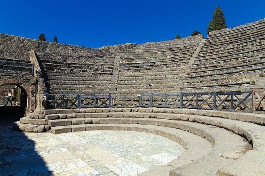 Un antiguo anfiteatro con escalones de piedra y un escenario central. 3