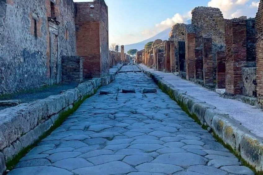 Una calle adoquinada bordeada por edificios de ladrillo antiguos con una montaña al fondo. 1