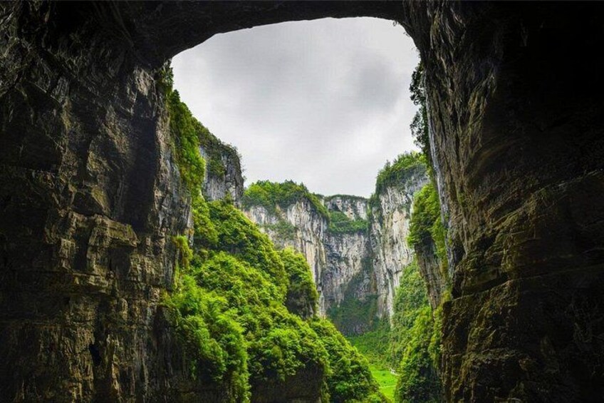 A canyon with lush greenery and a rock archway. 4