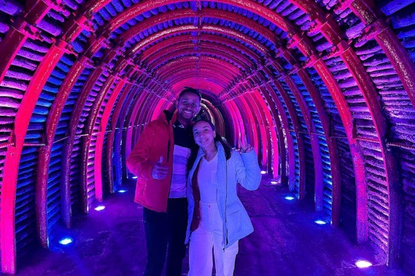A tunnel with a curved ceiling and illuminated by pink and blue lights. 1