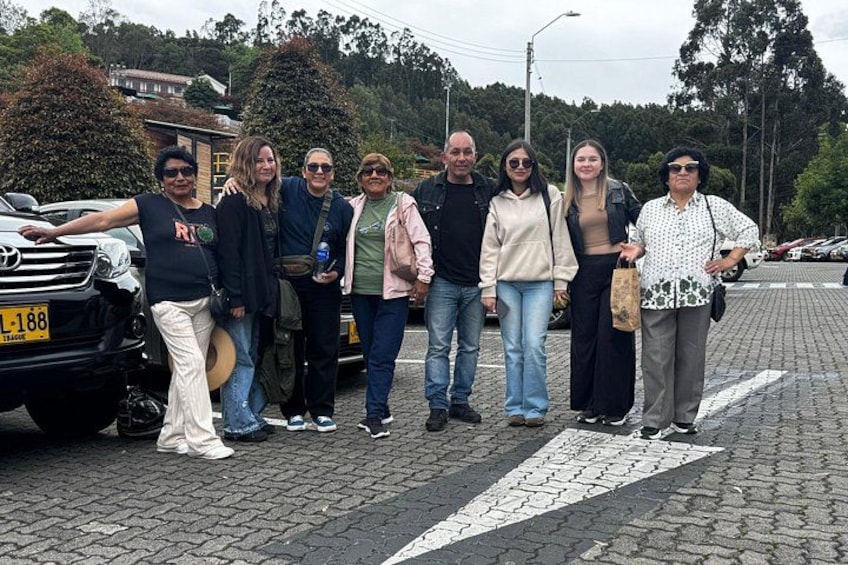 A group of people standing on a cobblestone street with a car parked nearby. 2