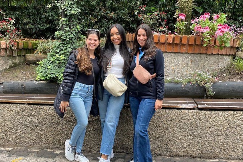 Three people standing in front of a garden with flowers and a brick wall. 3