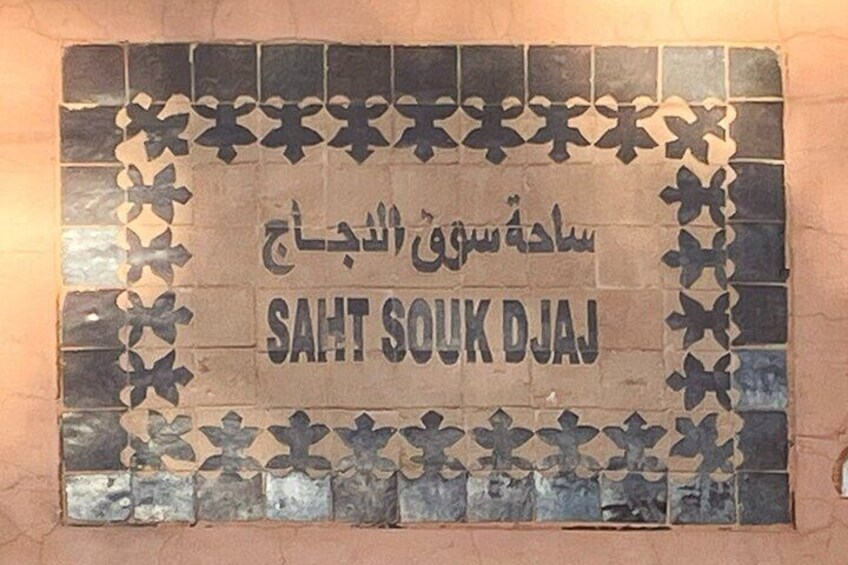 A tiled wall with the text "SAHT SOUK DJAJ" and decorative patterns. 3