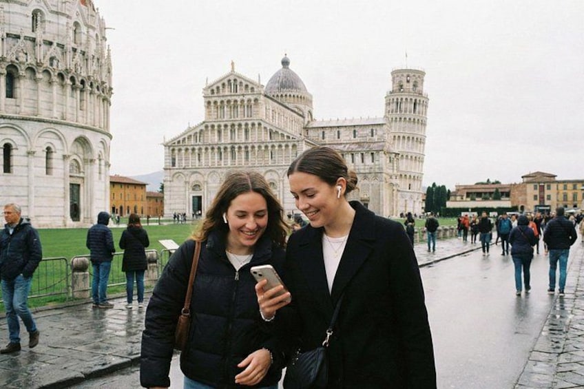 Two people standing in front of the Leaning Tower of Pisa, with the Pisa Cathedral in the background. 4