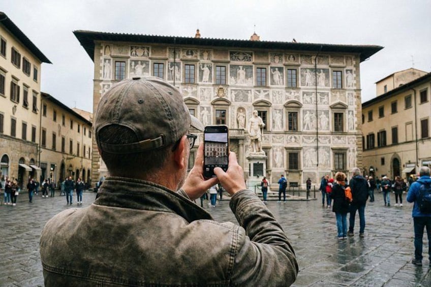 A person taking a photo of a historic building with intricate facade and statues. 2