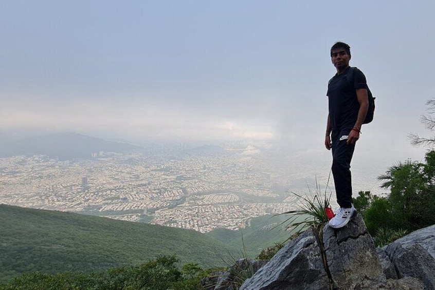 A person standing on a rocky outcrop overlooking a cityscape. 3