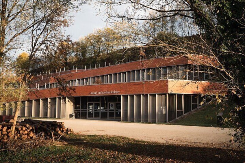 A modern building with a brick facade and large windows, surrounded by trees and a grassy area. 3