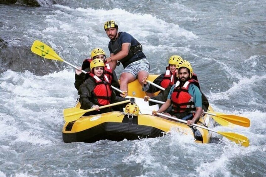 A group of people in a yellow raft navigating a river with rapids. 1