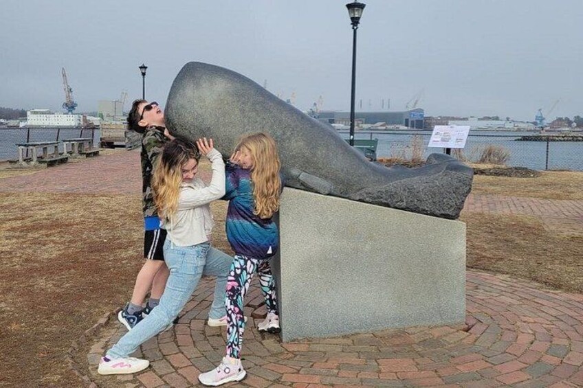 A group of people interacting with a large sculpture in an outdoor setting. 2