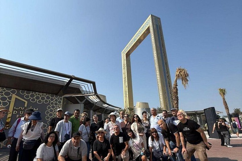 Un grupo de personas posando frente a un edificio moderno con una estructura de arco distintiva. 2