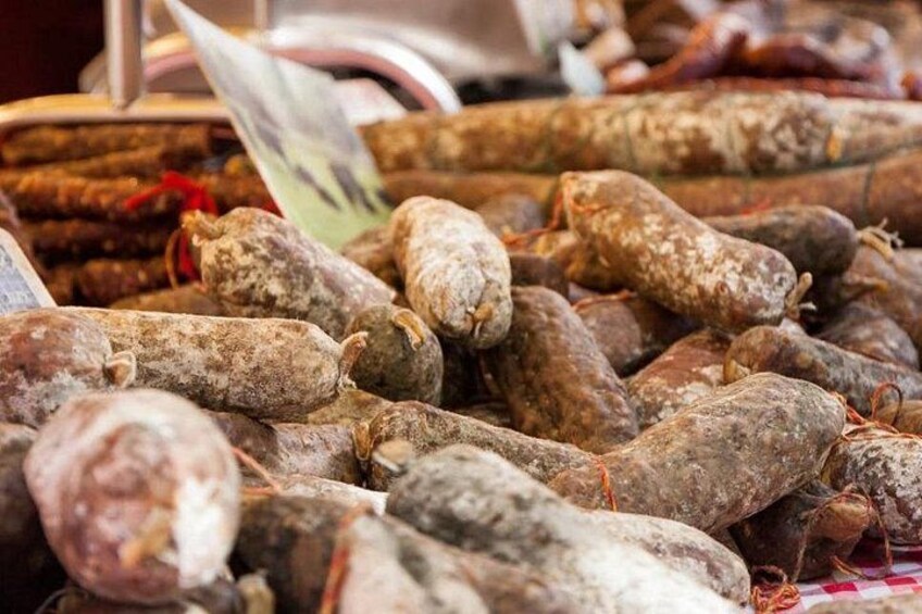 A variety of cured meats displayed at a market. 5