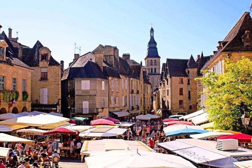 A bustling outdoor market with stalls and people. 1