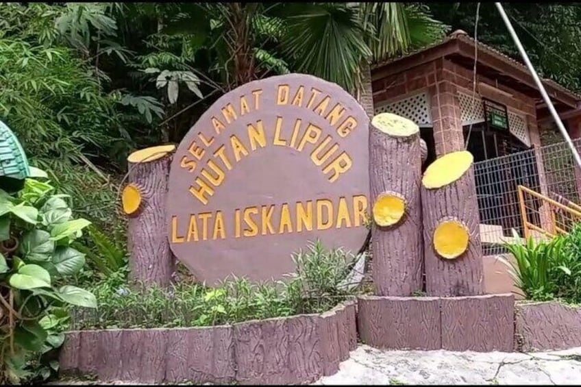 A sign with 'SELAMAT DATANG HUTAN LIPUR LATA ISKANDAR' surrounded by trees and a building. 1