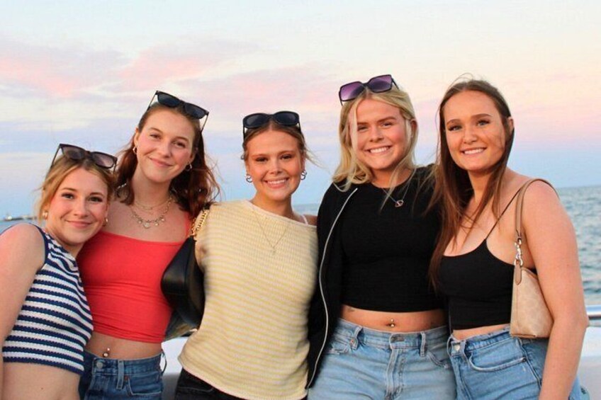 A group of people standing on a boat with a sunset in the background. 3
