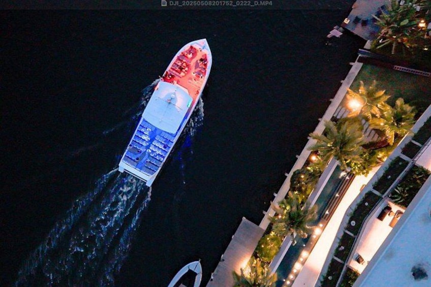 A speedboat with a red and white hull moving through water, with a building and palm trees in the background. 4