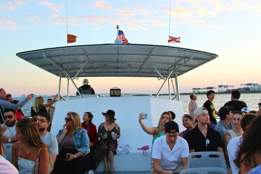 A boat with a covered deck, people on board, and a sunset in the background. 3