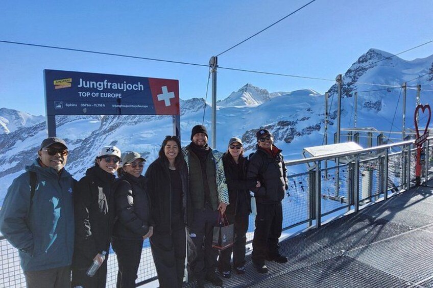 En gruppe mennesker står på en skilift med et skilt i baggrunden, der siger 'Jungfraujoch TOP OF EUROPE'. 5
