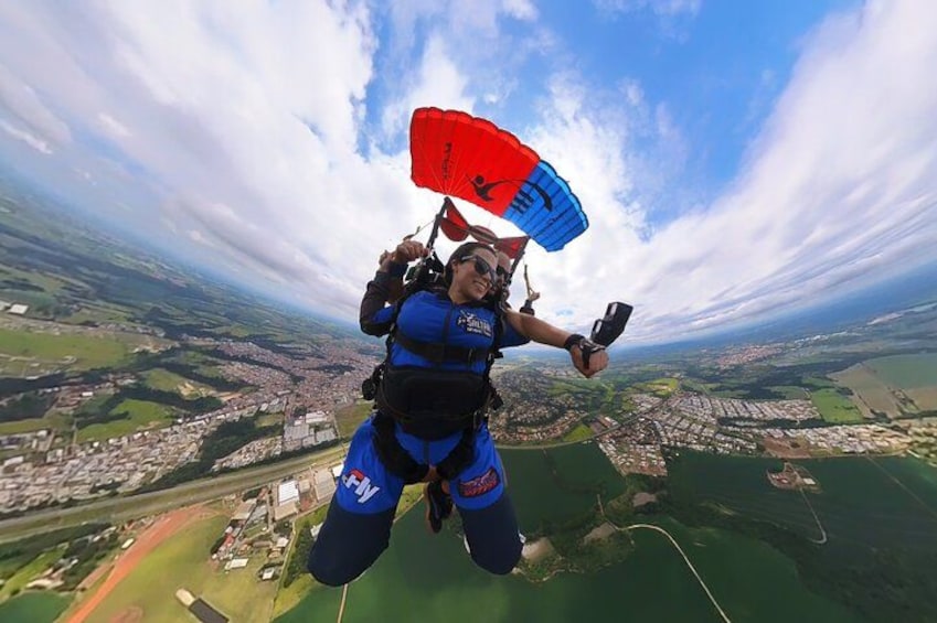 A person skydiving with a parachute above a cityscape. 1