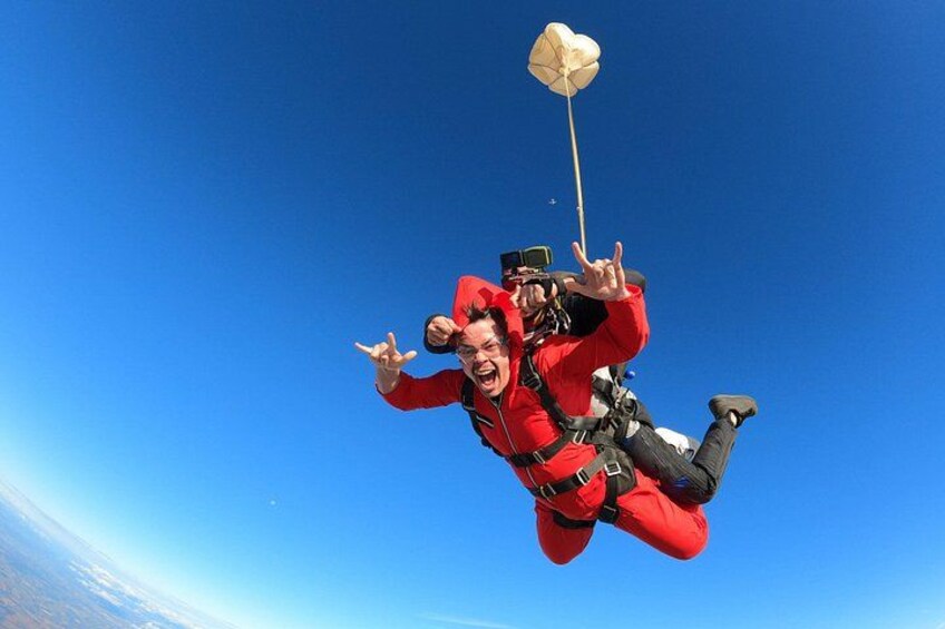 A person in a red jumpsuit with a parachute, sky, and Earth in the background. 5