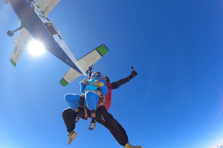 A person skydiving with a parachute, a clear blue sky, and a sun in the background. 3