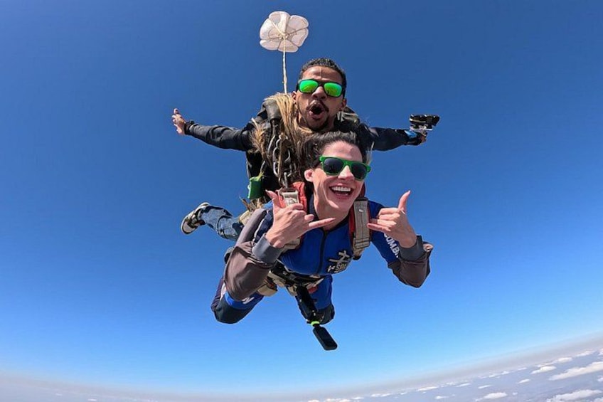 Two people skydiving with parachutes, one giving a thumbs-up. 2