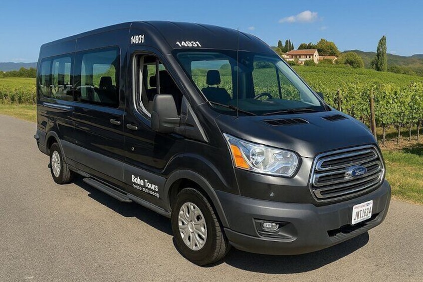 A black Ford Transit van with 'Boho Tours' branding parked on a road. 1
