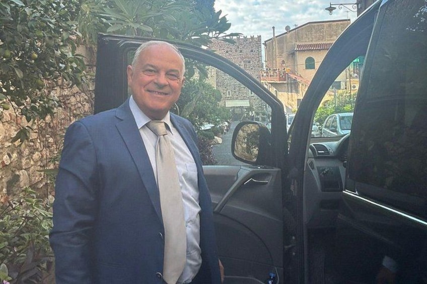 Un uomo in abito che sta accanto a una portiera dell'auto aperta. 4