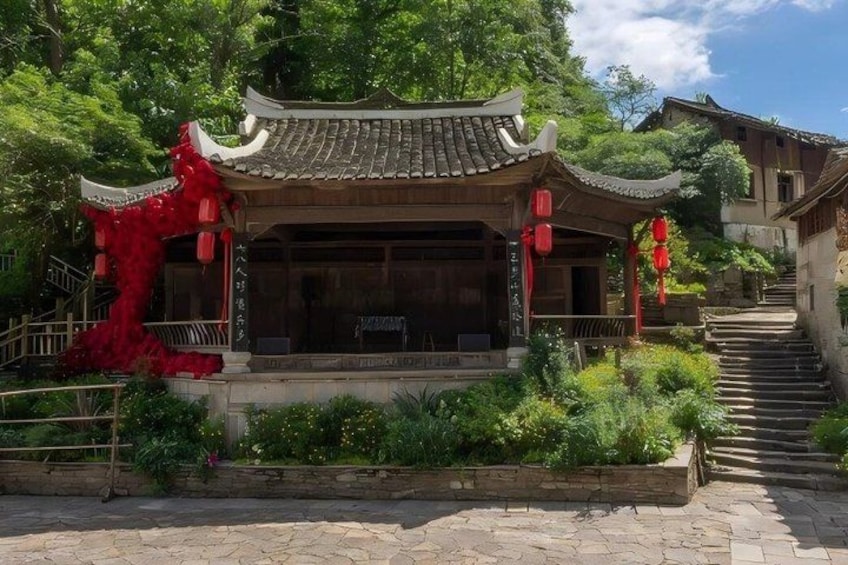 A traditional Chinese building with a tiled roof, surrounded by greenery and a stone staircase. 3