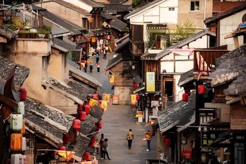 A narrow street lined with traditional buildings, some with sloped roofs and red lanterns. 5