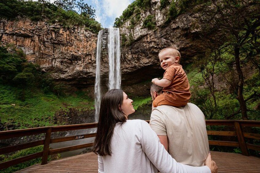 Een vrouw en een kind op een houten brug, met een waterval op de achtergrond. 3