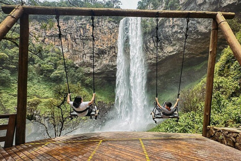 Twee personen op schommels met uitzicht op een waterval. 2