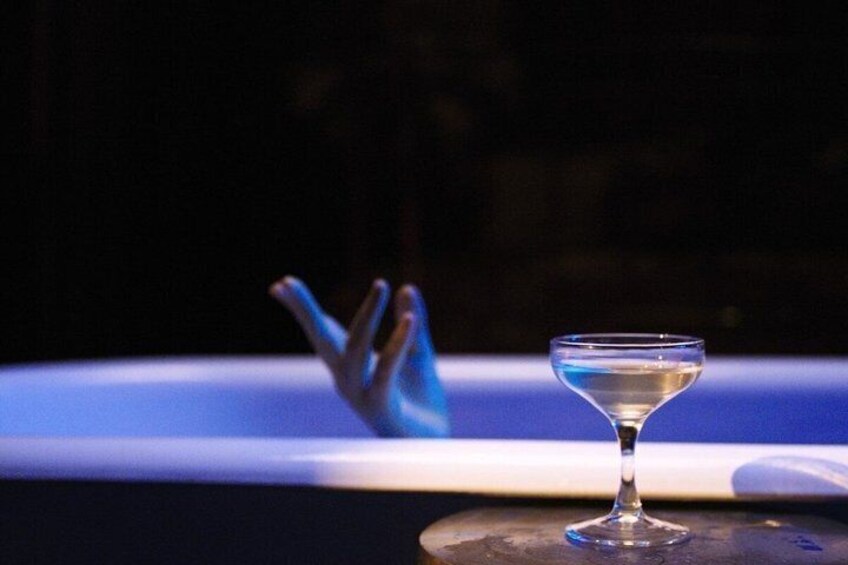 Un verre à martini posé sur une surface réfléchissante, avec un objet bleu flou en arrière-plan. 5