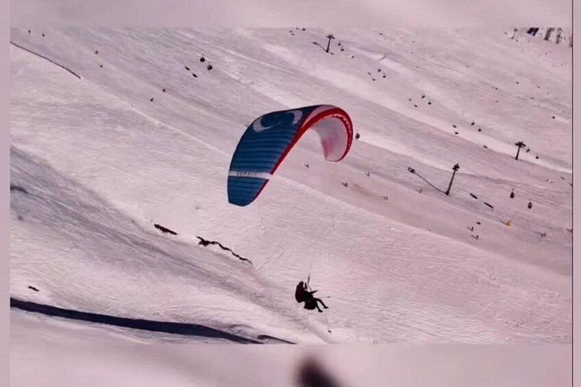 A person kiteboarding on a snowy slope with a blue and red kite. 1