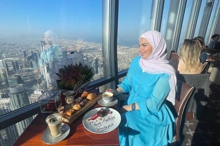 A person seated at a table with a city view, enjoying a meal with pastries and a drink. 4