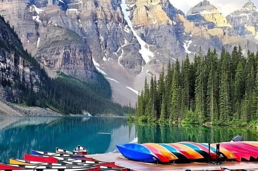 Un lac avec des montagnes en arrière-plan et des kayaks aux couleurs vives sur la rive. 3