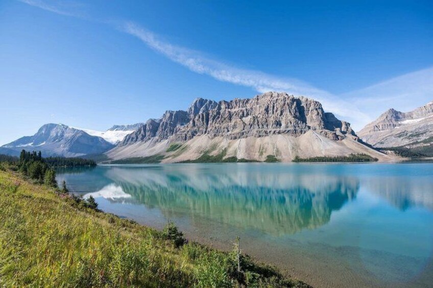Un lac de montagne aux eaux limpides, dont le miroir reflète les montagnes environnantes, qui sont à la fois escarpées et parsemées d’une végétation clairsemée. 4