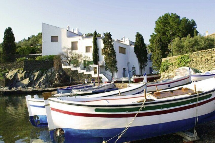 Una hilera de barcos amarrados en un puerto con un edificio blanco al fondo. 3