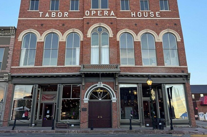 A brick building with arched windows and a sign that reads 'Tabor Opera House.' 3