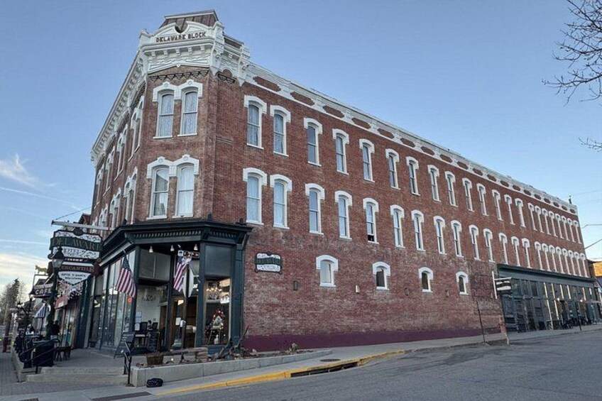 A historic brick building with a corner entrance, storefronts, and a street view. 5