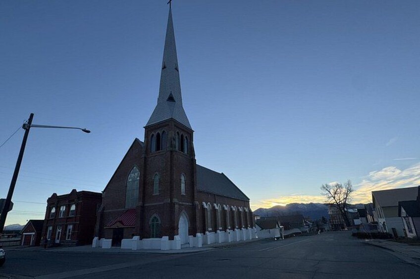 A church with a tall steeple, a red brick facade, and a cross at the top. 2