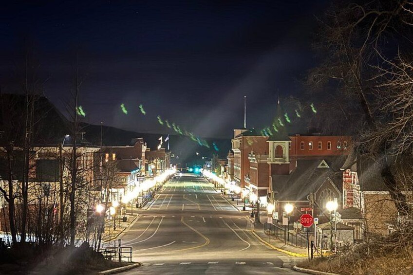 A nighttime street scene with illuminated buildings, a stop sign, and a road leading into the distance. 1