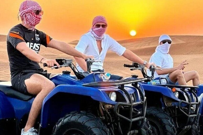 Three people on quad bikes in a desert landscape during sunset. 3