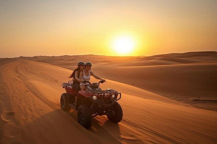 Two people on a quad bike in a desert with sand dunes and a setting sun. 2