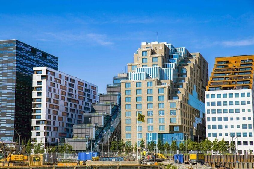 A cityscape with modern buildings, construction barriers, and a clear blue sky. 1