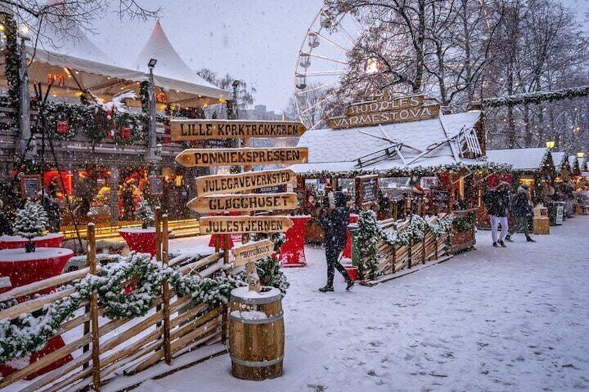 A snowy outdoor market with wooden signs and festive decorations. 2