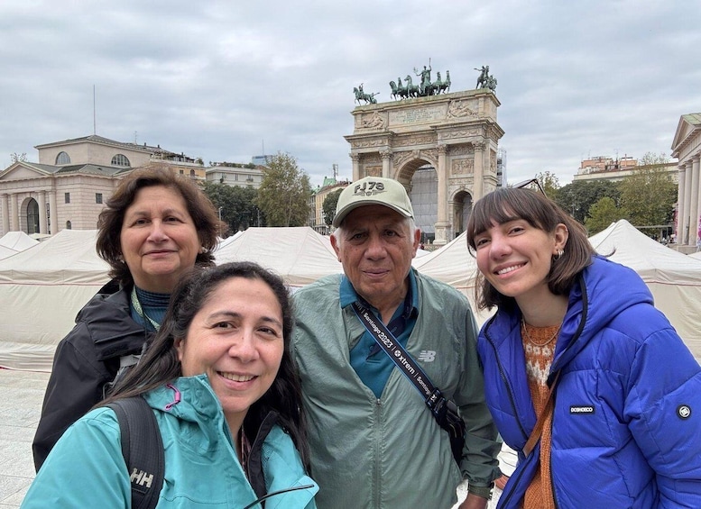 A group of people in front of a large historical monument with statues on top. 5