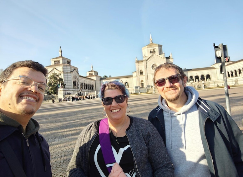 Three people standing in front of a large historical building with arches and domes. 1