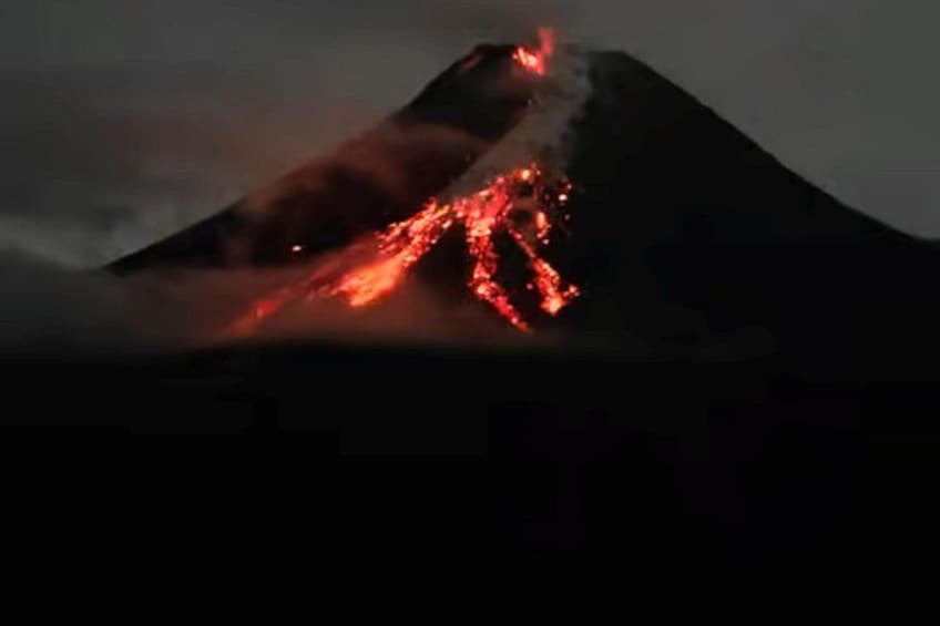 A volcano with lava flowing down its side. 1